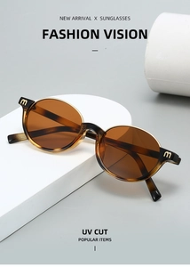 Détail de lunettes de soleil écaillées avec logo M doré sur la branche et verres bruns