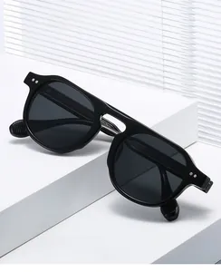 Détail de lunettes de soleil rondes avec rivets argentés et branches ondulées