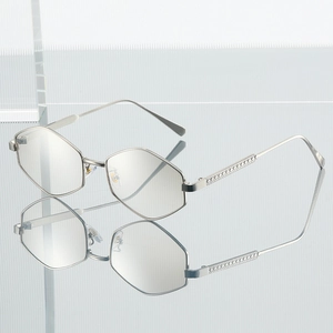 Modern hexagonal silver metal sunglasses with textured temples over a reflective surface