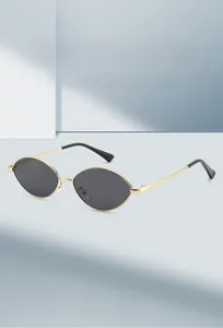 Detail view of oval metal sunglasses with gold frame and dark gray lenses at 45-degree angle