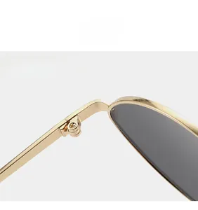 Detail of sturdy metal hinges on gold oval sunglasses with durable dark gray lenses