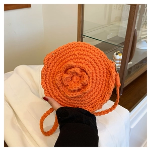 Detailed view of an orange round crochet shoulder bag featuring a 3D floral woven pattern