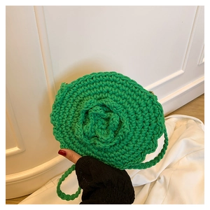 Detail of green handmade crochet round bag featuring a 3D floral rose design on knit surface