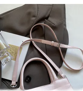 Pink croc-embossed leather tote bag with adjustable shoulder strap on art book