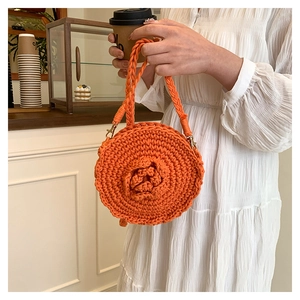 Detail of orange round hand-woven straw bag featuring textured spiral patterns