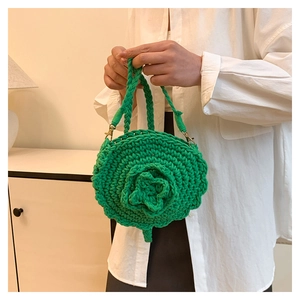 Detail of green handmade woven round handbag with 3D floral texture and gold hardware