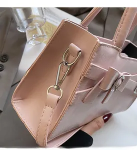 Detail of pink glossy leather handbag with gold hardware and elegant leather bow ornament
