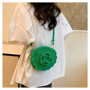 Detailed texture of green hand-woven round bag featuring large 3D floral crochet pattern