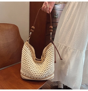 Détail du sac cabas tissé avec perles en bois, anses en cuir brun et détails frangés