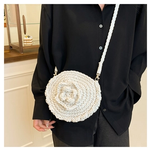 Detail of hand-woven round straw bag featuring a large 3D floral pattern and strap
