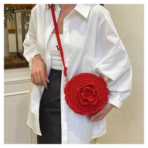 Detail of red handmade woven shoulder bag featuring 3D floral rose design on a model