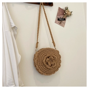 Detail of a handmade straw bag with large woven flower and metal hook shoulder strap