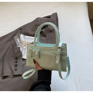 Detail of mint green leather bag featuring a bow ornament and adjustable shoulder strap