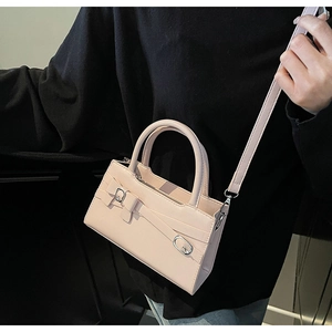 Detail of light beige crossbody bag featuring leather strap buckle and silver hardware
