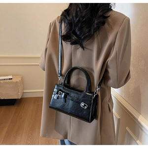 Detail of black PU leather tote with elegant bow accent and detachable crossbody strap
