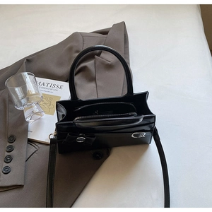 Detailed view of black glossy leather handbag with elegant bow and silver hardware