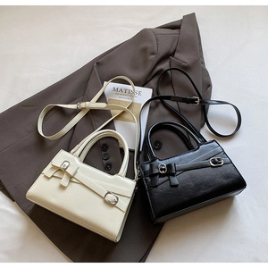 Close-up of retro cream and black square handbags with bow accents and fine texture