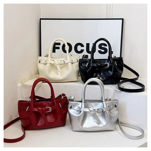 Detail view of four modern drawstring handbags in cream, black, burgundy, and silver finishes