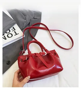 Detail of red glossy handbag with silver metal buckle and adjustable shoulder strap