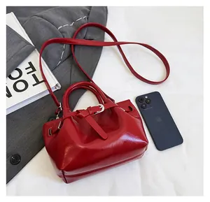 Detail view of red faux leather Boston bag with metallic buckle and adjustable strap