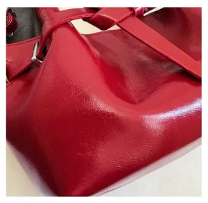 Macro shot of red glossy textured leather and adjustable buckle on woman's handbag
