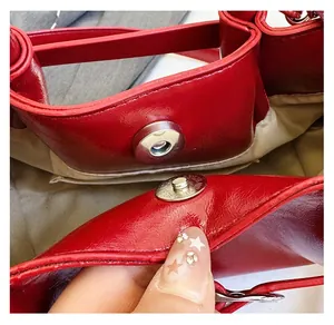 Detailed view of the magnetic silver snap closure on the red leather drawstring bag