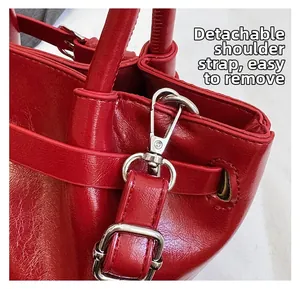 Detail of red patent leather bag with silver metal lobster clasp and removable strap