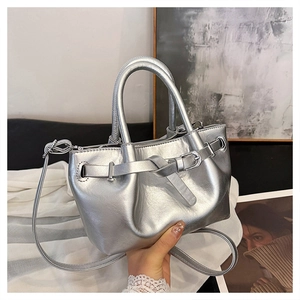 Detail of silver metallic tote bag with decorative buckle and dual carry straps