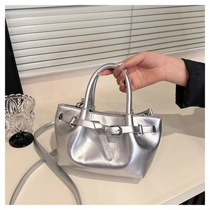 Detail of silver metallic drawstring handbag with adjustable strap and top handles