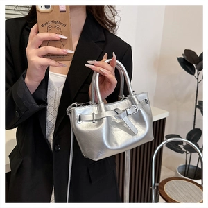 Detail of silver metallic handbag with decorative buckle and cylinder handle for daily use