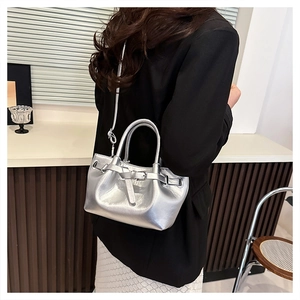 Detail view of a silver metallic handbag with decorative buckle and slim shoulder strap