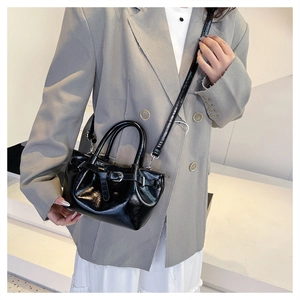 Polished black crossbody bag with drawstring design and slender shoulder strap on model