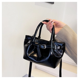 Detail of black glossy patent leather handbag with silver buckle and round handles