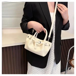 Detail of off-white glossy faux leather handbag with silver buckles and dual top handles