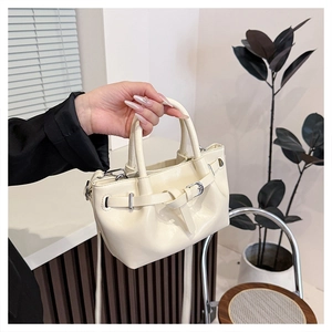 Detail of cream drawstring handbag with silver buckle held in a minimalist home setting