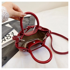 Detail view of red handbag interior with beige lining, side pocket, and magnetic snap closure
