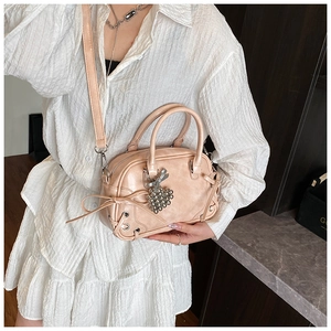 Détails du nœud et du pendentif cœur sur un sac à main Boston beige pour femme