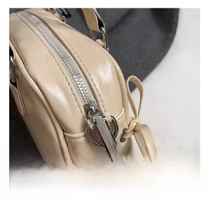 Détails de la fermeture éclair argentée et du nœud sur le sac Boston en cuir PU beige