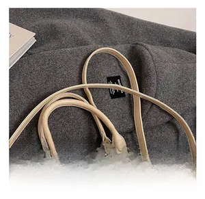 Détail du sac Boston crème avec bandoulière réglable et boucles métalliques