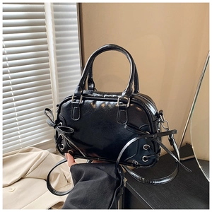 Détail du sac Boston en cuir noir brillant avec des nœuds latéraux et des œillets en métal