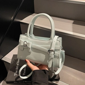 Retro light blue leather tote bag with bow detail on grey stairs scenery background