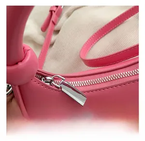 Detail einer rosa halbmondförmigen Handtasche mit silbernem Metallreißverschluss und Nähten