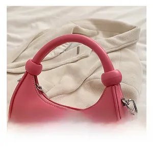 Detail der rosafarbenen Halbmond-Handtasche mit dickem Rundgriff und glattem Kunstleder