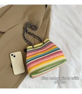 Size comparison of colorful woven handbag with metal chain strap next to a smartphone