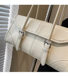 Detail view of cream-white PU leather shoulder bag with silver buckles and flap closure