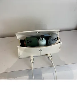 Spacious interior of off-white shoulder bag showing phone, umbrella, and cosmetics