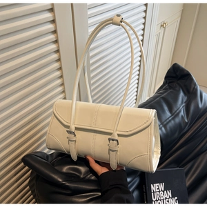 Detail of beige shoulder bag featuring dual buckle straps and thin elegant handles