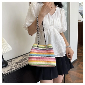 Close-up of a vibrant rainbow striped woven handbag with silver chain strap on shoulder