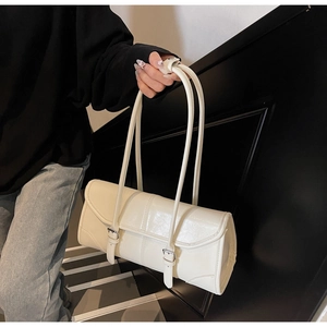 Detail shot of the cream shoulder bag featuring double buckle straps and glossy finish