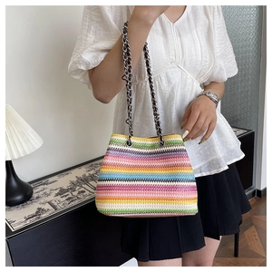 Detail of colorful striped woven crossbody bag with metallic chain strap and handcrafted texture